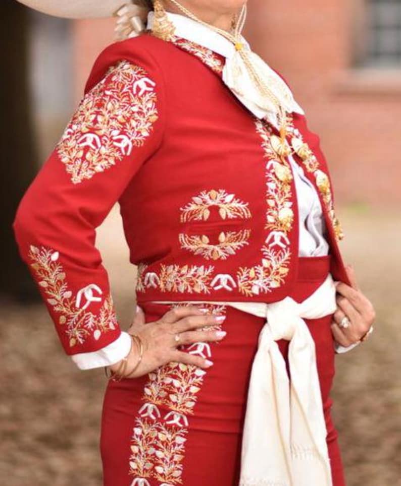 May include: A red embroidered jacket with white and gold detailing. The jacket has a white collar and a white sash tied at the waist.