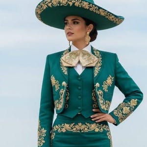 May include: A teal mariachi outfit with gold embroidery. The ensemble includes a wide-brimmed hat, a jacket, a vest, and a skirt. The jacket and skirt feature intricate gold floral patterns. The outfit is completed with a gold bow tie and matching earrings.
