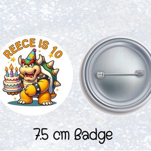 May include: A 7.5 cm badge featuring a cartoon character holding a birthday cake with candles. The text "REECE IS 10" is displayed above the character. The badge has a pin back.