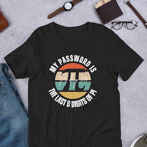 Peut inclure: T-shirt noir avec un motif graphique coloré. Le motif présente le texte "MY PASSWORD IS" au-dessus d'un symbole Pi stylisé et le texte "THE LAST 8 DIGITS OF PI". Le symbole Pi est orange, sarcelle et jaune.