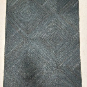 Może przedstawiać: Dywan tkany w ciemnoniebieskim kolorze z geometrycznym wzorem. Dywan wykonany jest z naturalnych włókien i ma fakturowaną powierzchnię.