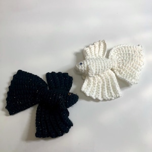 Op de afbeelding: Twee gehaakte betta-vissen, een zwart en een wit. De vissen zijn gemaakt van garen en hebben gedetailleerde vinnen.