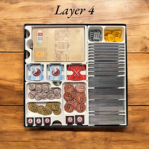 May include: Layer 4 of a board game organizer insert. The insert has compartments for cards, tokens, and other game components. The insert is made of white plastic and has a black border. The text "Layer 4" is printed on the top of the insert.