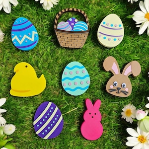 May include: A collection of Easter decorations, including a basket filled with colourful eggs, a yellow chick, a pink bunny, and several decorated eggs. The decorations are arranged on a bed of green grass.