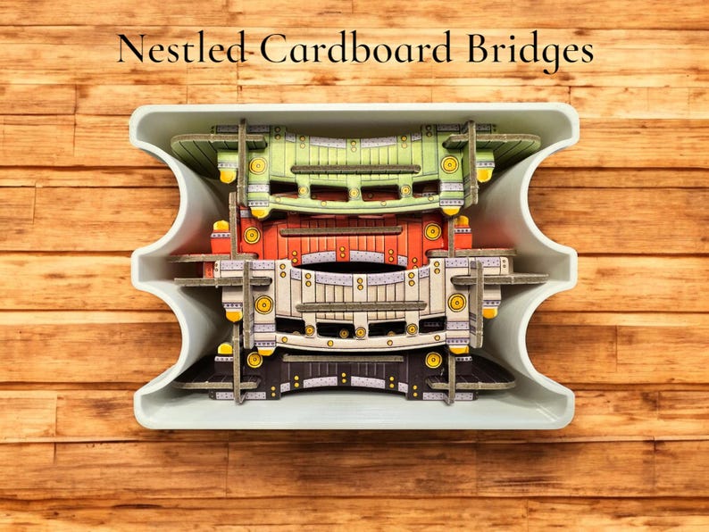 May include: Four cardboard bridges, each with a different color and design, are stacked inside a white container. The bridges are green, red, white, and black.