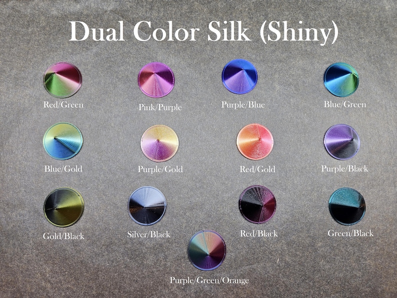 May include: A collection of 14 dual color silk fabric samples, each with a different color combination. The samples are arranged in a grid pattern and labeled with the color combinations, such as "Red/Green", "Pink/Purple", "Purple/Blue", "Blue/Green", "Blue/Gold", "Purple/Gold", "Red/Gold", "Purple/Black", "Gold/Black", "Silver/Black", "Red/Black", "Green/Black", and "Purple/Green/Orange".