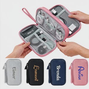 May include: Pink zippered travel organizer with multiple compartments, holding various electronic accessories like cables and a power bank. Below are four smaller cases in gray, black, navy, and pink, each with a name embroidered on the front.