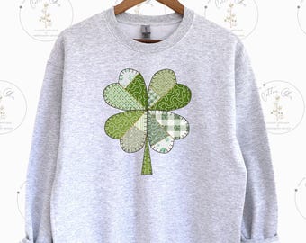 May include: A gray sweatshirt with a green four-leaf clover design. The clover is made up of different green patterned fabric pieces.