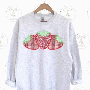 May include: A gray sweatshirt with a red and green embroidered design of three strawberries.