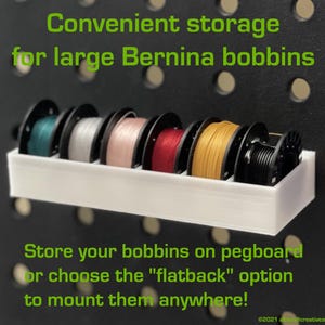 May include: A white bobbin holder with six spools of thread in various colors, including teal, silver, pink, red, gold, and black. The text reads "Convenient storage for large Bernina bobbins." and "Store your bobbins on pegboard or choose the "flatback" option to mount them anywhere!"