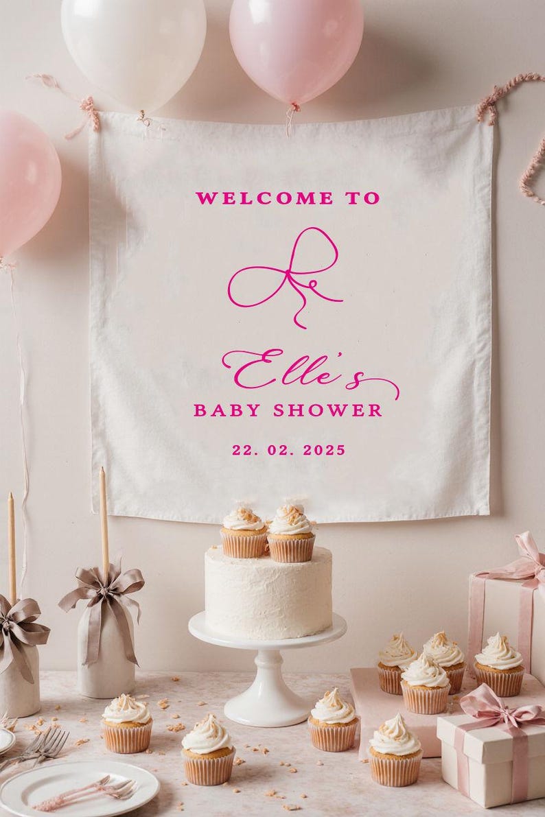 May include: A baby shower scene with a banner that reads "Welcome to Elle's Baby Shower 22.02.2025." The table is set with a cake, cupcakes, gifts, and balloons. The cake is white with two cupcakes on top.