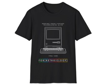 Puede incluir: Camiseta negra con un contorno blanco de una computadora y un teclado vintage. El texto "KEEPING THESE VINTAGE TECHNOLOGIES ALIVE" está por encima de la computadora y "1984 128K FOR(RETRO)[LOOP]" está debajo de la computadora.