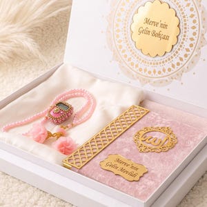 May include: A white gift box containing a pink velvet-covered book with gold accents, a digital prayer counter, and pink beaded prayer beads. The box lid features gold text reading Merve'nin Gelin Bohçası, while the book cover displays the text Merve'nin Gelin Mevlidi.