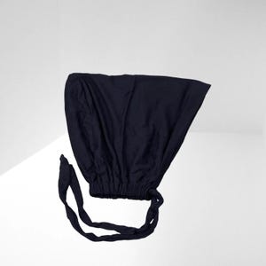 May include: A dark blue fabric bonnet with a gathered elastic band and two long ties.