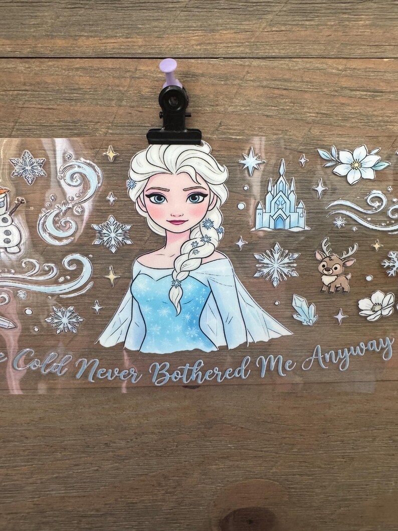 May include: A clear sticker featuring a cartoon illustration of a princess with white hair and a blue dress. The sticker includes snowflakes, a castle, and the text "The Cold Never Bothered Me Anyway."