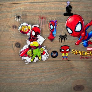 K&ouml;nnte beinhalten: Eine Sammlung von Spider-Man-Artikeln, darunter Aufkleber, Anstecknadeln und eine kleine Figur. Die Artikel zeigen den Superhelden in seinem charakteristischen rot-blauen Anzug. Der Hintergrund ist eine Holzoberfl&auml;che.