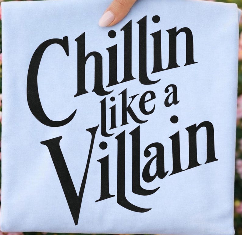 Puede incluir: Una camiseta azul claro con el texto negro "Chillin like a Villain" impreso en una fuente serif audaz y estilizada en el centro. Las letras est&aacute;n dispuestas en tres l&iacute;neas con una ligera orientaci&oacute;n diagonal para las palabras superior e inferior.