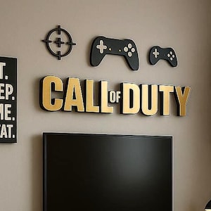 Op de afbeelding: Een slaapkamer met een gamingthema. De muur is versierd met "CALL OF DUTY" in gouden letters, controllerkunst en de tekst "EAT. SLEEP. GAME. REPEAT." Een bed met een patchwork quilt, een bureau, een tv en planken met boeken zijn ook zichtbaar.