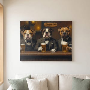 Custom pet portrait canvas propped on a living room sofa, showing three bulldog-type dogs in grey suits and black bow ties side by side at a wooden bar, each with a pint of beer, warm lamps and a hanging wooden bar sign behind them. Personalized Irish bar dog art made from your own photos.