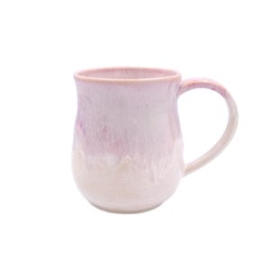 Puede incluir: Una taza de cerámica rosa y blanca con cuerpo redondeado y asa. La taza tiene un esmalte que crea un efecto jaspeado.