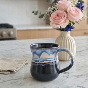 Taza de cerámica artesanal con diseño de olas costeras: Gres esmaltado en negro y azul.