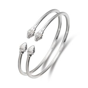 May include: Two silver bangle bracelets with decorative, pointed ends. The ends are detailed with a floral design.