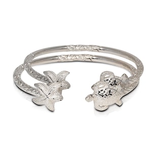 May include: A silver bangle bracelet with a turtle and two starfish designs. The bracelet is made of two bands of silver that are intertwined.