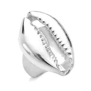 May include: A silver ring shaped like a cowrie shell. The ring is smooth and shiny, with a detailed design on the outside of the shell.