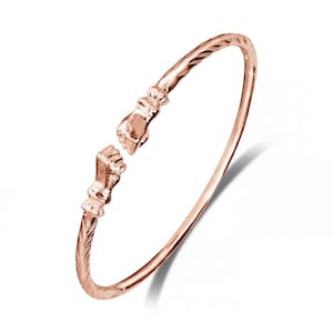 Könnte beinhalten: Offener Armreif aus Roségold mit detaillierten handförmigen Enden. Das Armband hat ein strukturiertes Design am Band und ist vor einem weißen Hintergrund platziert. Das Armband ist ein Schmuckstück.