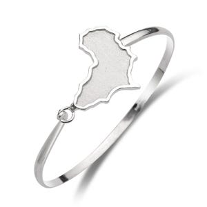 May include: A silver-colored bangle bracelet featuring a map of Africa. The map is a solid, textured design. The bracelet has a simple, elegant design, with a smooth, polished finish. The bracelet is a piece of jewelry.
