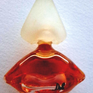Peut inclure: Un petit flacon en verre transparent avec un bouchon en verre givré. Le flacon est rempli d'un liquide orange vif. Le flacon a un design unique et facetté.