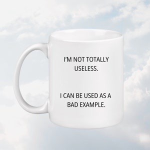 May include: White ceramic mug with black text that reads "I'm not totally useless. I can be used as a bad example."