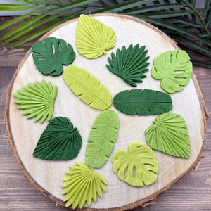 May include: A collection of 12 green and yellow leaf-shaped decorations. The leaves are made of a soft, pliable material and are perfect for adding a touch of nature to crafts and projects.