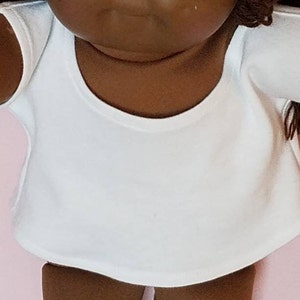 May include: A white sleeveless doll shirt with a scoop neck.