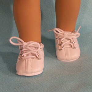 May include: White leather doll shoes with silver eyelets and white laces.