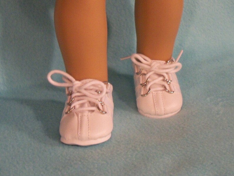 May include: White leather doll shoes with silver eyelets and white laces.