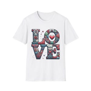May include: White t-shirt featuring the word "LOVE" in a colorful, patchwork design. The letters are filled with various patterns, hearts, and geometric shapes in red, green, and blue. A heart is in the center of the "O".