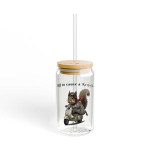 Könnte beinhalten: Ein klares Glas mit Bambusdeckel und einem durchsichtigen Strohhalm. Der Becher zeigt eine skurrile Illustration eines Eichhörnchens mit Pilotenmütze und Schal, das einen Roller fährt. Der Text auf dem Glas lautet: "Off to cause a Kerfuffle."