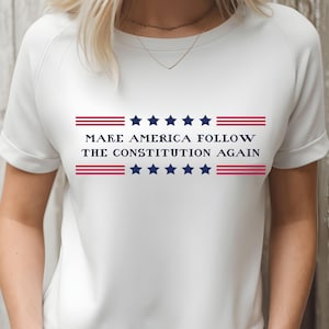 May include: White t-shirt with the text "MAKE AMERICA FOLLOW THE CONSTITUTION AGAIN" in navy blue and red. The design includes navy blue stars and red stripes, creating a patriotic theme.