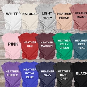May include: A collection of short-sleeved t-shirts in various colors, including white, pink, red, and black. Each shirt displays a different color name in bold, uppercase letters. The shirts are neatly arranged, showcasing a range of hues.