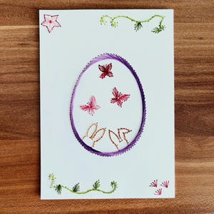 Kaart met geborduurde paasmotieven, lentedecoratie met konijnen, vlinders en bloemen