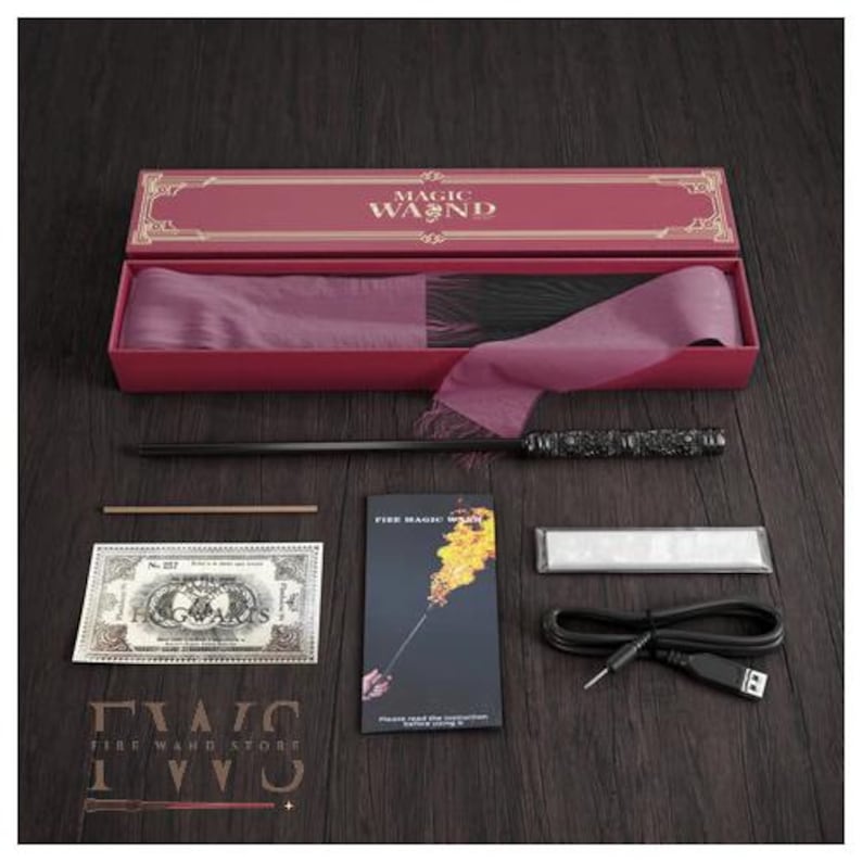 May include: A magic wand set in a red box with the words "MAGIC WAND" on the lid. The set includes a black wand, a prop bill, instructions, a charging cable, and other accessories. The wand has intricate detailing.