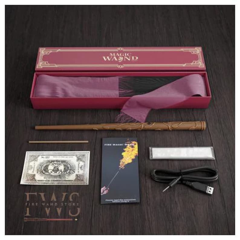 May include: A magic wand set with a brown wand, a pink box with the words "MAGIC WAND", a booklet, a prop bill, and a charging cable. The wand has intricate carvings and is displayed on a dark wooden surface.