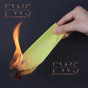 May include: A hand holds a yellow strip of material, with flames engulfing the bottom edge. The image has the text "FIRE WAND STORE" and a wand graphic. The background is a dark, solid color.