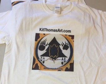 May include: White t-shirt with a brown, yellow, and black graphic design featuring a tree and bear paw prints. The text "KitThomasArt.com" is printed on the graphic and below it.