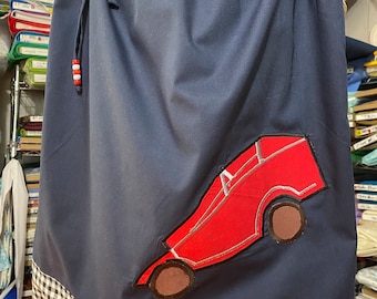 May include: A navy blue skirt with a red car applique. The skirt has a white and black checkered trim.