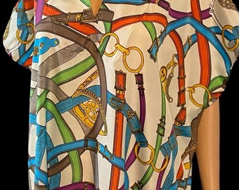May include: A hooded, short-sleeved dress featuring a colorful pattern of belts, buckles, and chains in shades of red, blue, green, and brown on a white background. The dress has a V-neck and a relaxed fit.