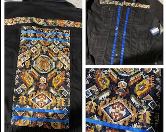 May include: A black denim jacket with blue ribbon accents and a colorful geometric pattern on the back. The pattern is reminiscent of a traditional rug or tapestry.