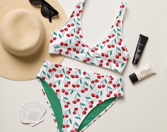 May include: A white bikini with a cherry print. The top is a triangle style and the bottom is a high-waisted style. The bikini is on a white background.