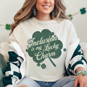 May include: A white sweatshirt with a green shamrock design and the text "Inclusion is my Lucky Charm".